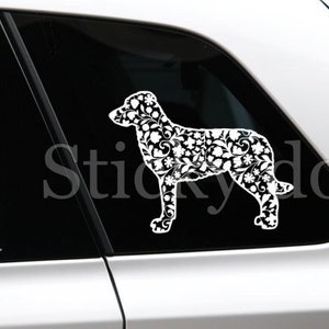 May include: A white car with a black and white floral dog silhouette decal on the back window. The decal says "Stickydog" in the background.