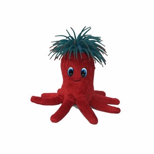Peut inclure: Une pieuvre en peluche rouge avec une crinière hérissée bleu et verte. La pieuvre a un visage souriant avec des yeux bleus.