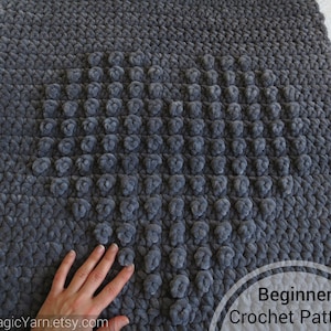 May include: A gray crochet blanket with a heart-shaped pattern of raised stitches. The text "Beginner Crochet Pattern" is visible in the lower right corner of the image.