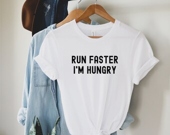 May include: White t-shirt with black text that reads "Run Faster I'm Hungry".