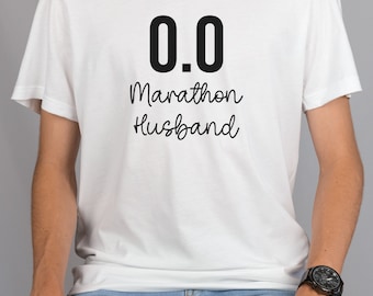 May include: White t-shirt with black text that reads "0.0 Marathon Husband".