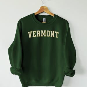 May include: A dark green sweatshirt with the word "VERMONT" in a white outline on the front.