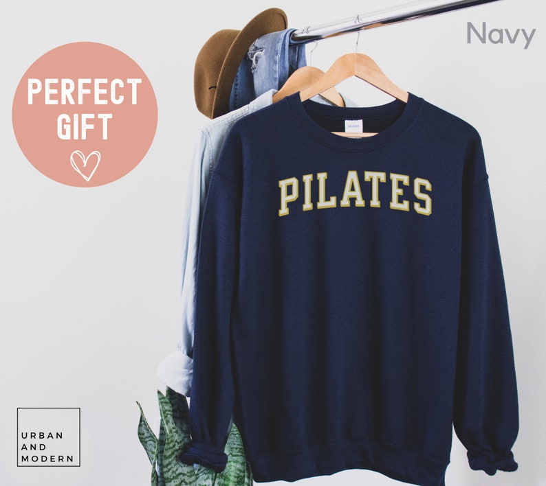 May include: Navy blue sweatshirt with the word "PILATES" in gold lettering.