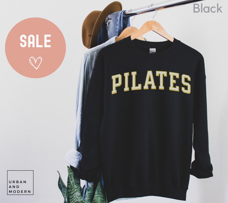 May include: Black sweatshirt with the word "PILATES" in gold lettering.