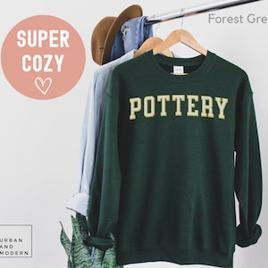 May include: Forest green sweatshirt with the word "POTTERY" in gold lettering.