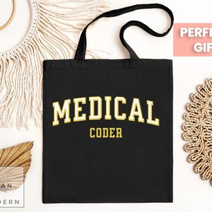 May include: Black tote bag with the text "MEDICAL CODER" in yellow letters. The bag has a black handle and is made of canvas.