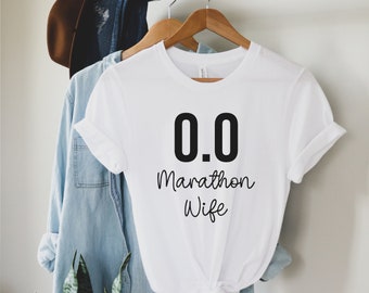 May include: White t-shirt with black text that reads "0.0 Marathon Wife".
