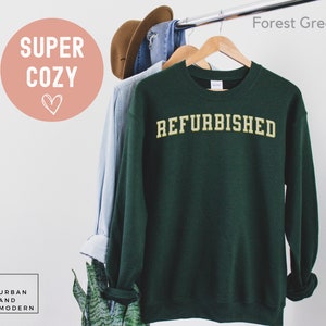 May include: Forest green sweatshirt with the word "REFURBISHED" in a gold-colored font.