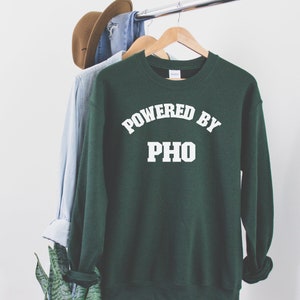 May include: A dark green sweatshirt with white text that reads "Powered by Pho".