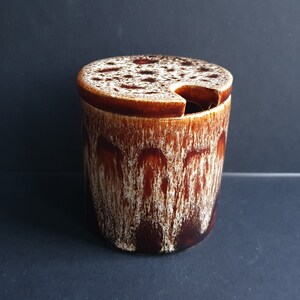 May include: A brown and white ceramic sugar bowl with a lid. The lid has a small spout for pouring.