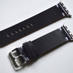 May include: Two black leather watch bands with white stitching and silver clasps. The bands are designed for Apple Watches.