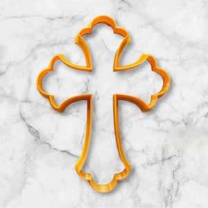 May include: A yellow plastic cross cookie cutter with a decorative design.