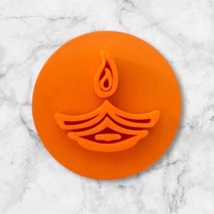 May include: Orange plastic cookie cutter shaped like a diya, a traditional Indian oil lamp.