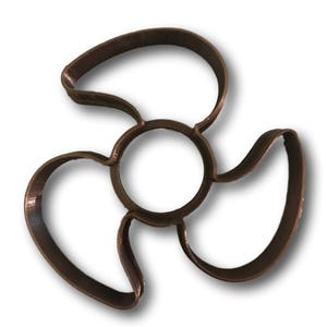 May include: A brown plastic cookie cutter shaped like a three-bladed propeller.