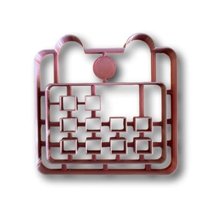 Könnte beinhalten: Ein brauner Plastik-Ausstecher in Form eines Kalenders mit einem Kreis oben und einem Gitter aus Quadraten.