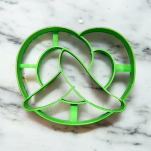 Puede incluir: Un cortador de galletas de pretzel de plástico verde.