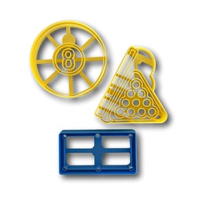 May include: Three yellow plastic cookie cutters shaped like a pool ball rack, a pool ball with the number eight, and a pool table. There is also a blue plastic cookie cutter shaped like a rectangle.