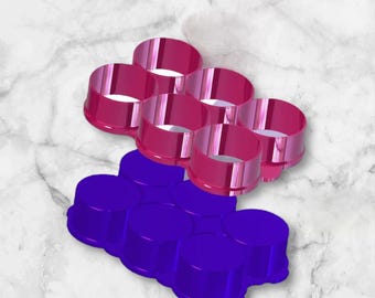 May include: Two sets of six round, plastic molds. The top set is pink and the bottom set is purple.