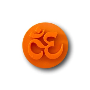 May include: Orange plastic cookie cutter shaped like the Om symbol.