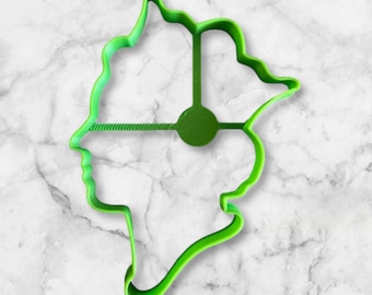 May include: Green plastic cookie cutter shaped like a person's face. The cutter has a detailed outline of a face with a simple design inside.