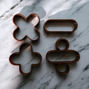 May include: Four brown plastic cookie cutters shaped like a plus sign, a minus sign, a division sign, and a multiplication sign.