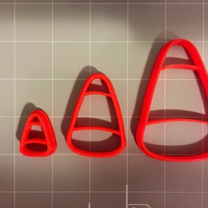 May include: Three red plastic candy corn cookie cutters of different sizes.
