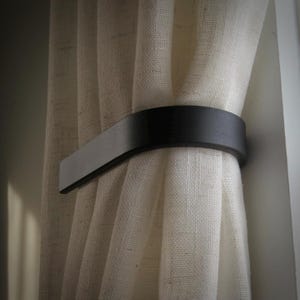 6 Inch curtain tie back in flat black...semi-sheer drapes. Flat wood trim (shown) is ideal but tiebacks can also be mounted to drywall using provided anchors and matching screws.