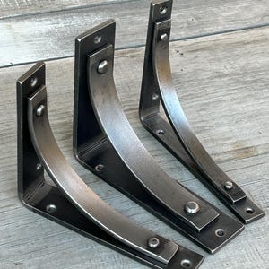 Our Station line of bracket...from left to right, Station Extra, Station Grande and Station all in 6" size and clearcoat over a paint ready finish. Displayed on weathered pine slab table.