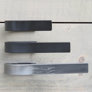 May include: Three metal door handles in different finishes. The top handle is black, the middle handle is black, and the bottom handle is a brushed nickel finish.