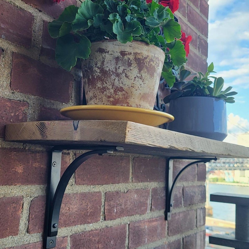 Customer image of 6 inch Station shelf brackets against brick with wood shelf support for potted plants.