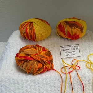 May include: Two balls of yarn in shades of yellow, orange, and red. The yarn is 98 yards long and weighs 2.82 ounces. The yarn is 78% acrylic and 22% nylon.