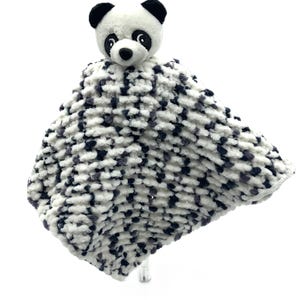 May include: A white and black panda plush toy attached to a white and gray knitted baby blanket. The blanket is soft and fluffy.