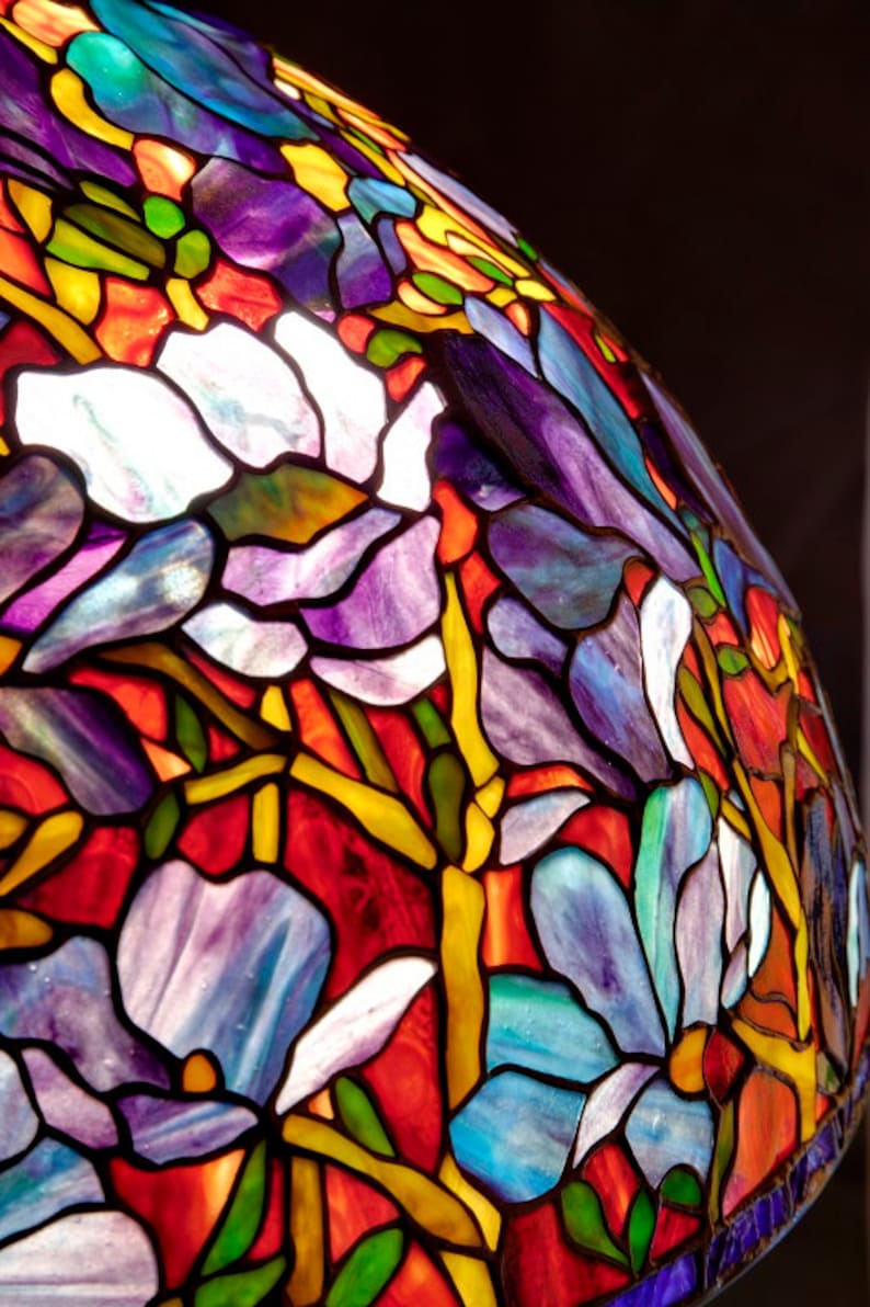 May include: A stained glass lampshade with a floral design. The shade features a variety of colors, including red, blue, purple, yellow, and green. The flowers are stylized and have a whimsical feel.