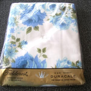 Puede incluir: Una s&aacute;bana blanca empaquetada en pl&aacute;stico transparente con un estampado floral azul y hojas verdes. La etiqueta dorada dice Fieldcrest, Duracale, Fine Combed All Cotton Percale y 72 x 108 Twin Flat. La s&aacute;bana est&aacute; doblada cuidadosamente dentro del pl&aacute;stico.