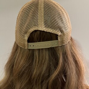May include: A brown mesh baseball cap with a black brim and a brown adjustable strap in the back.