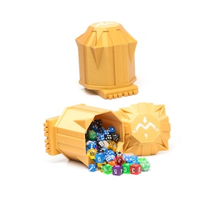 May include: A gold dice tower with a white symbol on the top. The tower is open and spilling out colorful dice.