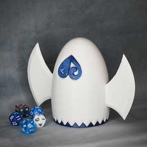 May include: White ceramic dice tower with blue wings and a blue heart design. The tower is surrounded by blue and white dice.