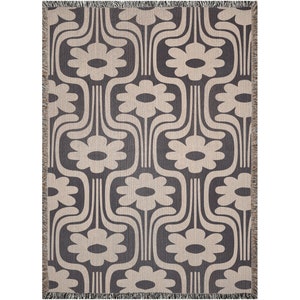 May include: A woven throw blanket with a geometric pattern of stylized flowers in beige on a dark gray background.