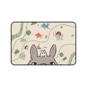 May include: A rectangular mat featuring a cartoon illustration. The design includes a gray rabbit with large ears, surrounded by colorful sea creatures and insects on a beige background with green lines.