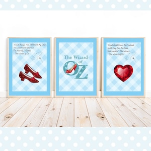 Puede incluir: Tres impresiones enmarcadas con un fondo a cuadros azul y blanco. La primera impresión presenta un par de zapatillas rojas de rubí y una cita del Mago de Oz. La segunda impresión presenta las palabras "El Mago de Oz" con una zapatilla roja de rubí. La tercera impresión presenta un corazón rojo de rubí y una cita del Mago de Oz.