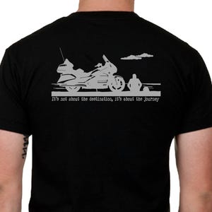May include: Black t-shirt featuring a motorcycle graphic and the text "It's not about the destination, it's about the journey." The graphic includes a motorcycle, a person, and clouds. The shirt is made of a soft material.