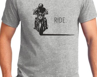 May include: Gray t-shirt featuring a black graphic of a motorcycle and rider. The word "RIDE" is printed to the right of the motorcycle. The shirt is made of a soft, comfortable material.