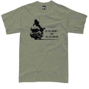 May include: Olive green t-shirt featuring a black graphic of a motorcycle with two riders. The text "ITS THE JOURNEY NOT THE DESTINATION" is printed below the motorcycle. The shirt has short sleeves and a crew neck.