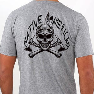 May include: Gray t-shirt featuring a black graphic of a skull wearing a Native American headdress, crossed tomahawks, and the words "NATIVE AMERICAN" in a semi-circle above and below the skull.