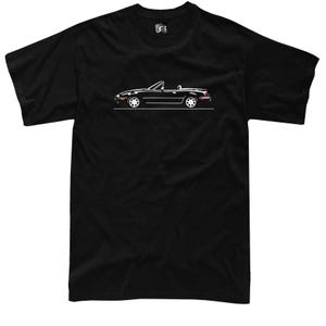 Könnte beinhalten: Schwarzes T-Shirt mit einer weißen Umrisszeichnung eines Cabriolets. Das Auto ist im Profil dargestellt, mit Details wie Rädern und Fenstern. Das Design ist auf dem T-Shirt zentriert und kontrastiert mit dem schwarzen Stoff. Das T-Shirt hat einen Rundhalsausschnitt und kurze Ärmel.