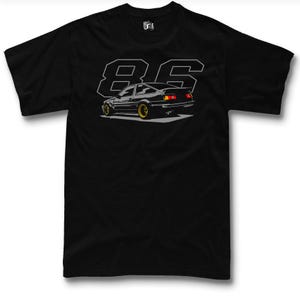 May include: Black t-shirt with a graphic of a black car with gold wheels, and the number "86" in grey. The car has a spoiler and is set against a grey background. The shirt has a crew neck.