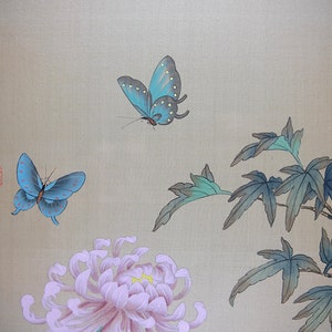 Puede incluir: Una pintura de inspiraci&oacute;n asi&aacute;tica con dos mariposas azules con puntos blancos, un gran crisantemo rosa y hojas verdes y azules. El fondo es de color beige claro y hay caligraf&iacute;a asi&aacute;tica en el lado izquierdo.