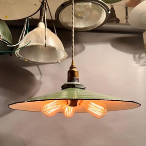 May include: A green metal pendant light fixture with three exposed light bulbs. The light fixture has a wide, flat, saucer-shaped shade.