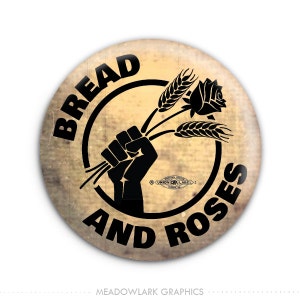 May include: A black and white button with the text "Bread and Roses" in a circle around a raised fist holding a rose and wheat stalks. The button has a distressed, vintage look.