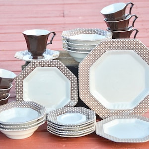 Puede incluir: Un juego de vajilla octogonal marrón y blanco con un patrón tejido. El juego incluye platos, cuencos y tazas.